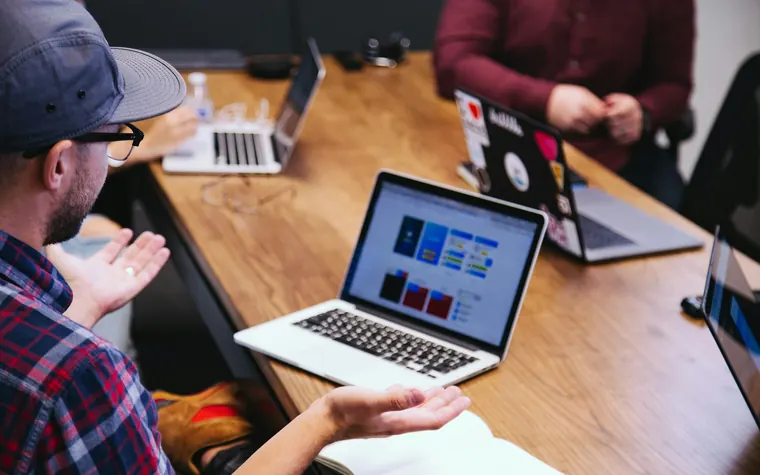 Reunión de trabajo alrededor de una mesa con notebooks abiertos